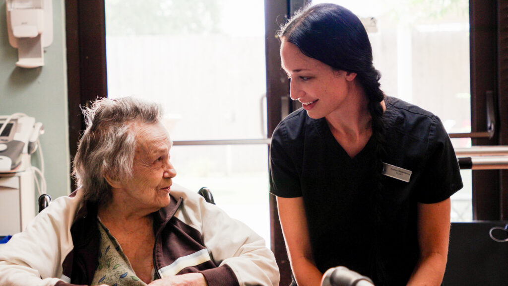 A nurse smiles at a memory care resident of a skilled nursing nursing home