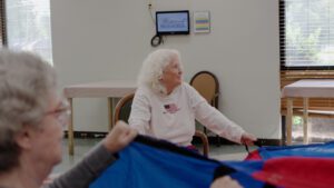 A woman smiles as she plays a game at a skilled nursing facility