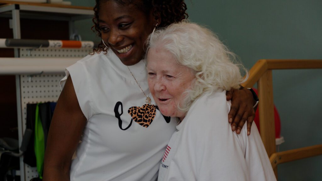 A staff worker at a skilled nursing care facility hugs a resident